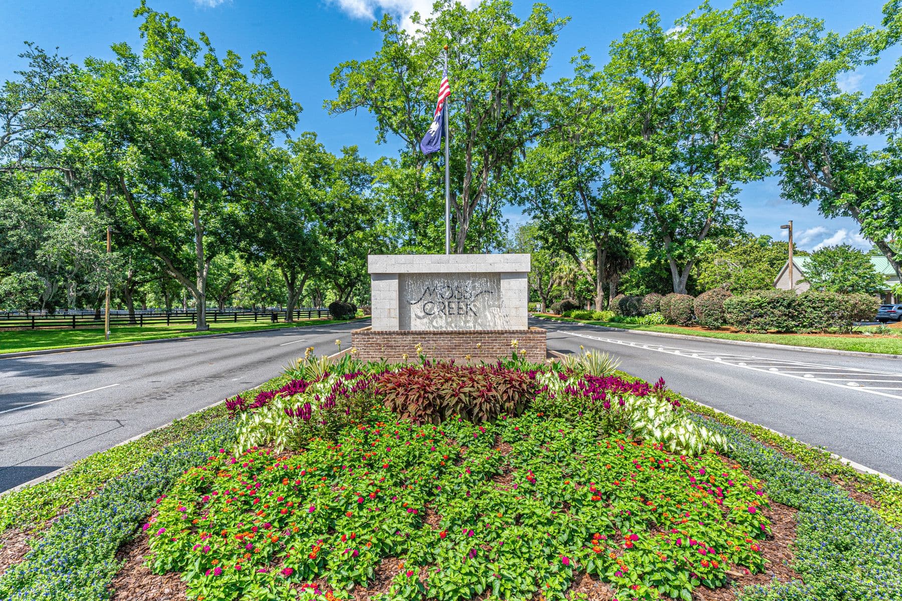 The landscaped entrance to Moss Creek in Bluffton, South Carolina, with flowering beds and flagpole