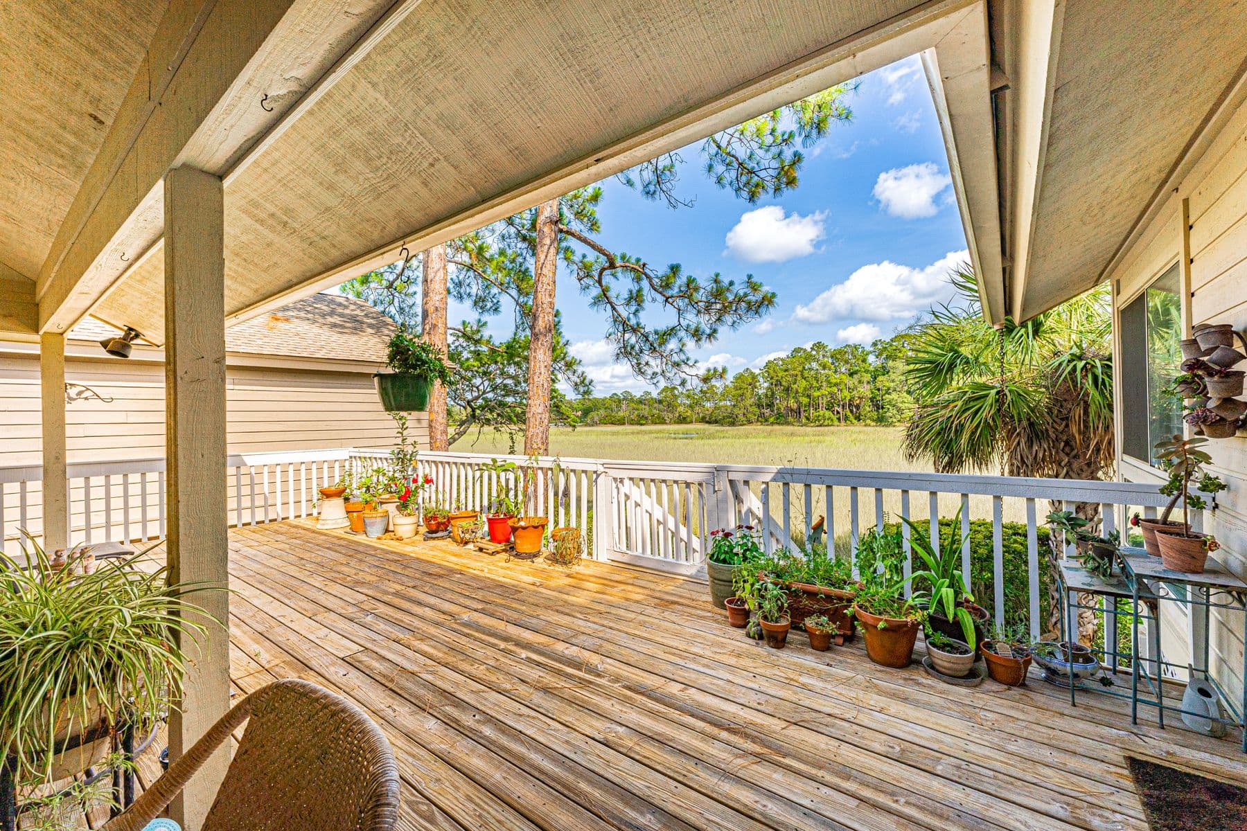 A covered porch with potted plants looking out over the marsh at a Moss Creek home