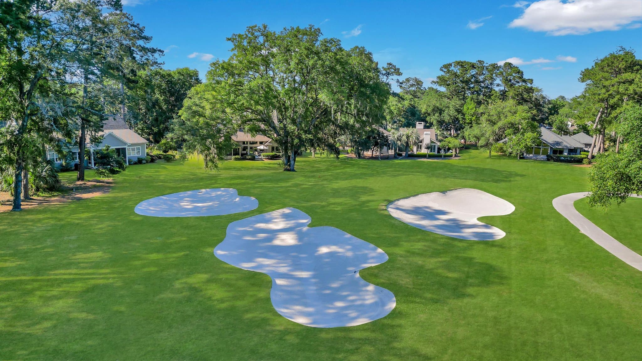 Aerial view of a golf hole and bunkers at Moss Creek, Bluffton, with homes along the fairway