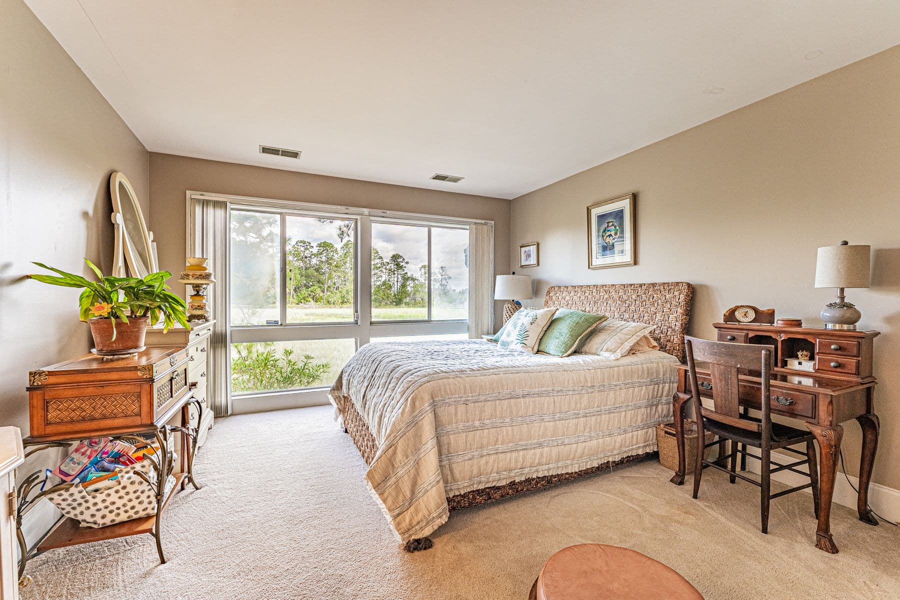A bedroom at 13 Marsh Winds with wide windows onto the trees