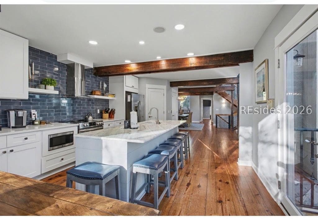 A kitchen with navy subway tile, a marble island and reclaimed beams in a Sea Pines townhouse
