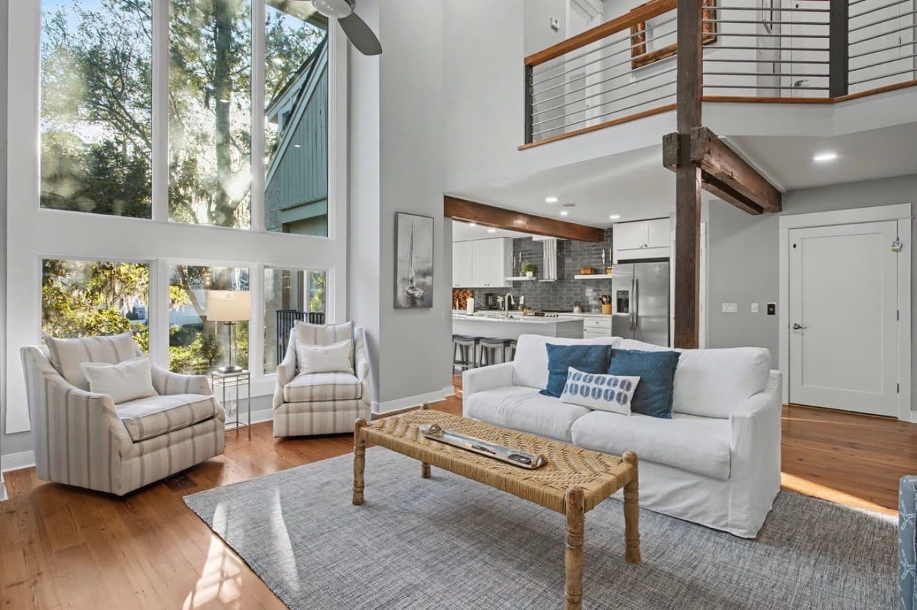 A double-height living room with exposed beams and tall windows in a Sea Pines townhouse
